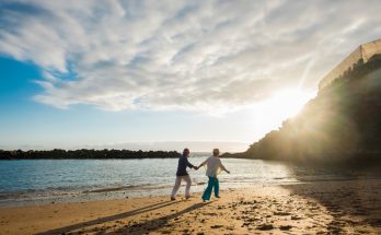 retired couple walking on a beach at sunset