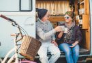 retired couple toasting each other with a coffee in a camper van