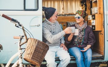 retired couple toasting each other with a coffee in a camper van