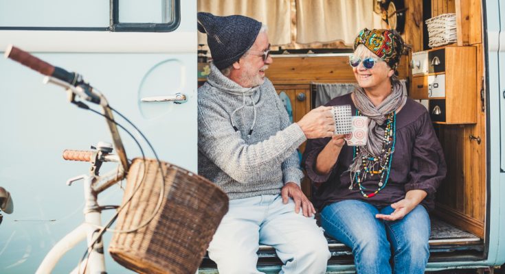 retired couple toasting each other with a coffee in a camper van